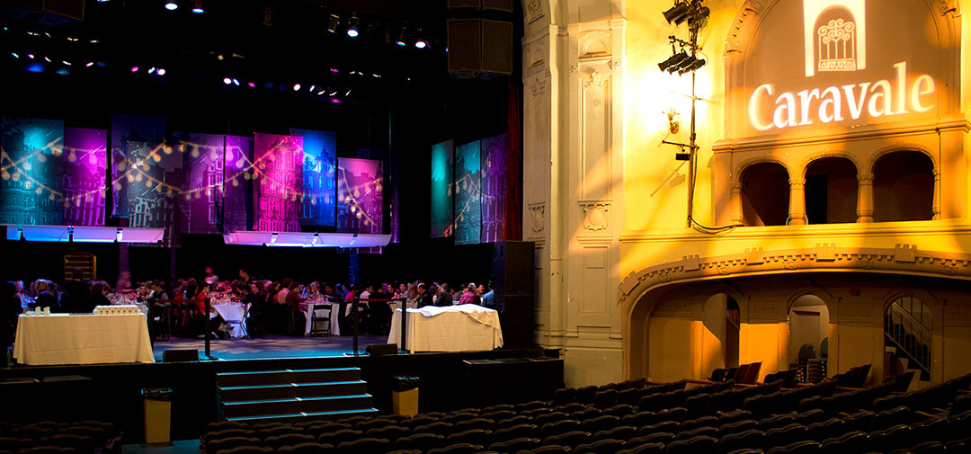 Photo of Caravale fundraising event at Moore Theatre with original artwork banners and custom gobo lighting