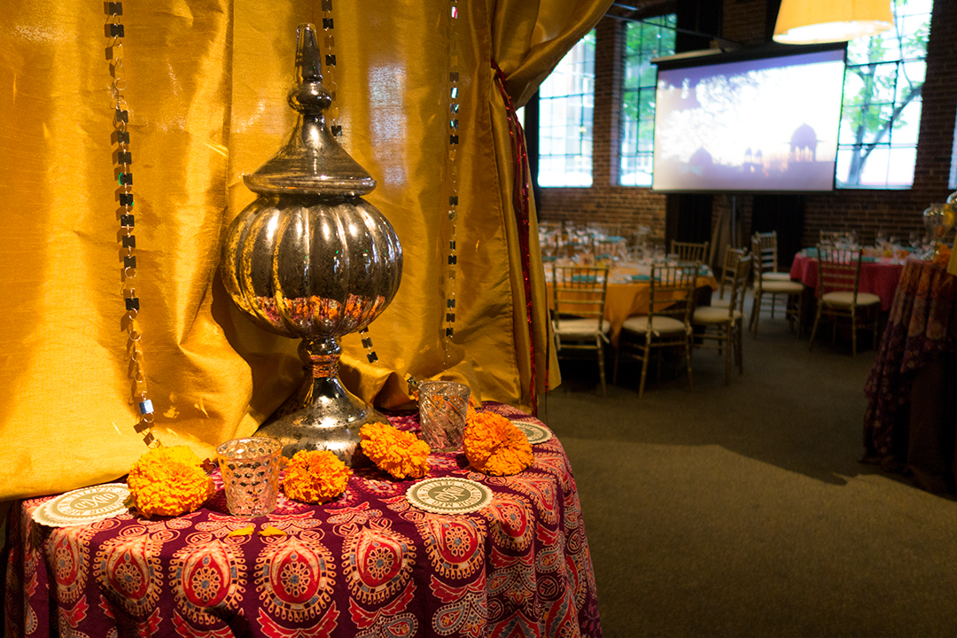 Caravale Neighborhood House event photo showing tabletop decorations and slideshow in the background